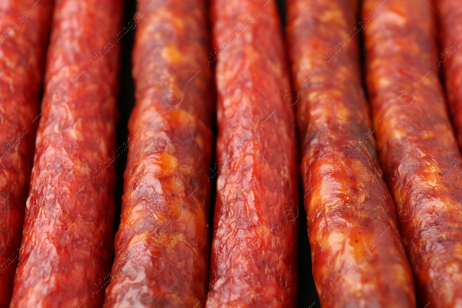 Photo of Different tasty smoked sausages as background, closeup