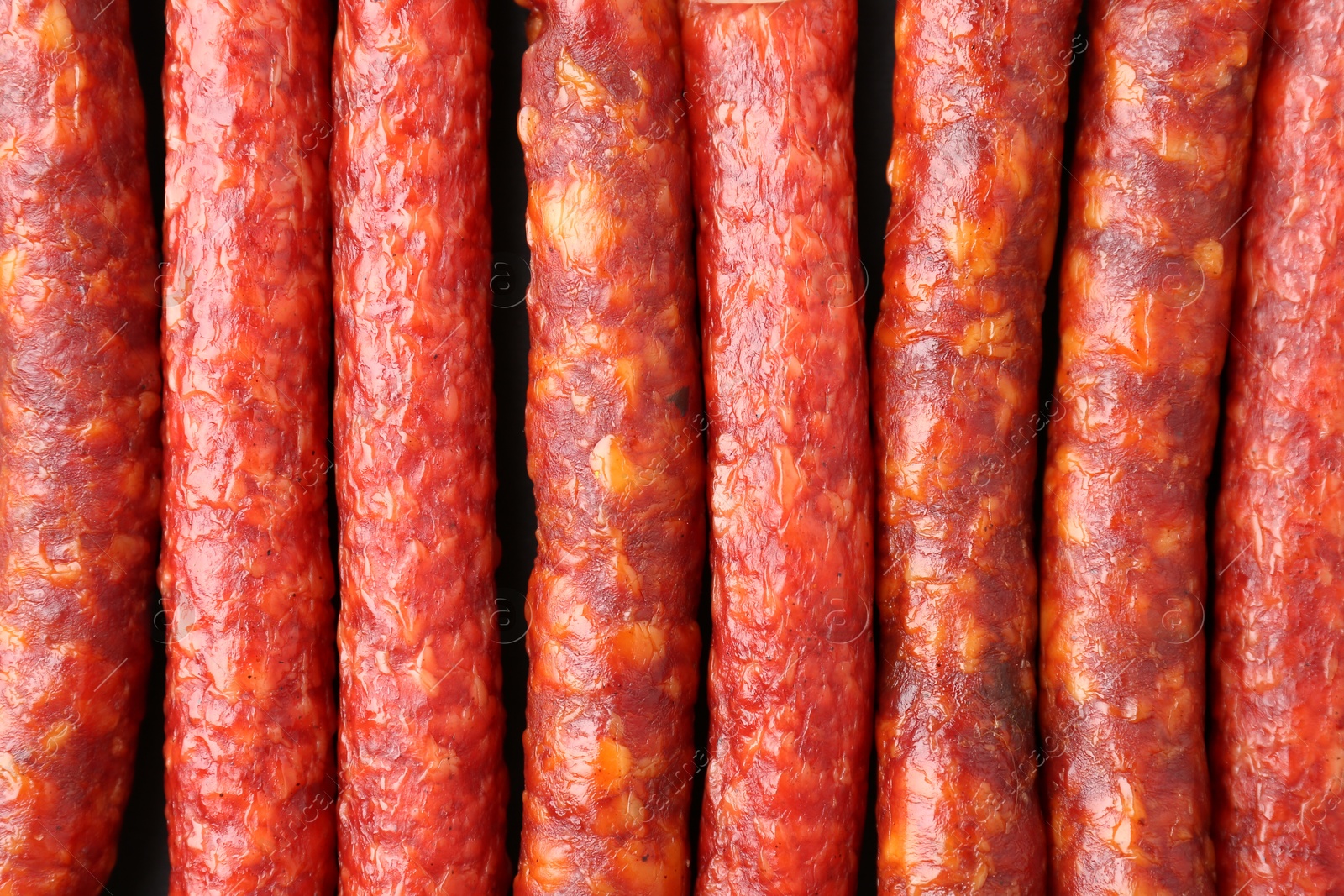 Photo of Many tasty smoked sausages as background, top view