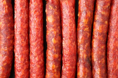 Photo of Many tasty smoked sausages as background, top view