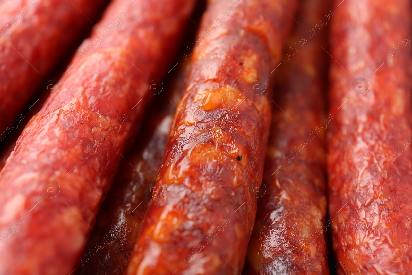 Photo of Different tasty smoked sausages as background, closeup