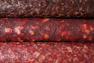 Photo of Different tasty smoked sausages as background, top view