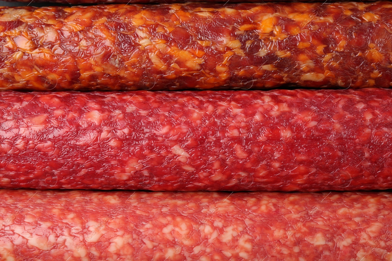 Photo of Different tasty smoked sausages as background, top view