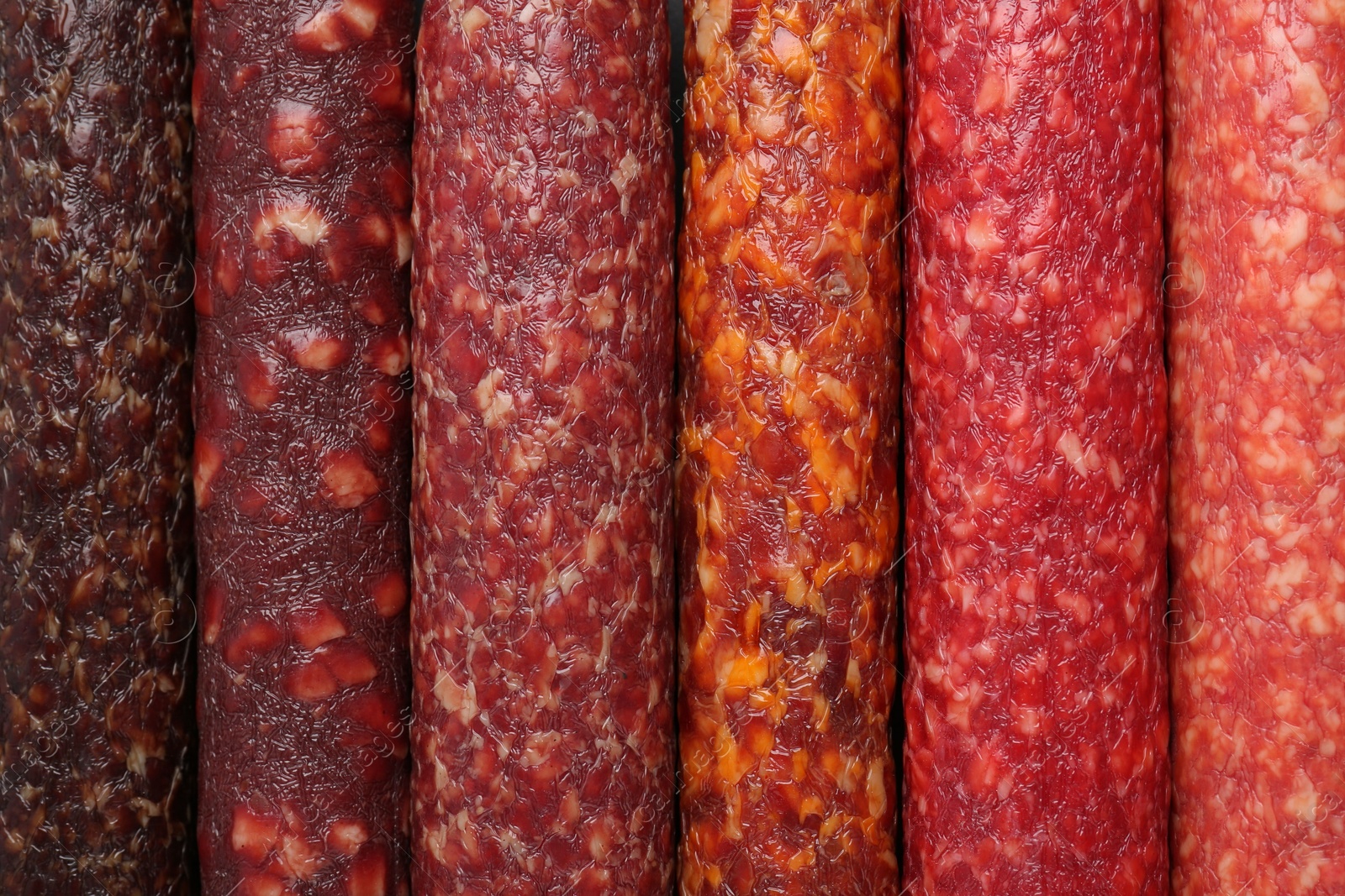 Photo of Different tasty smoked sausages as background, top view