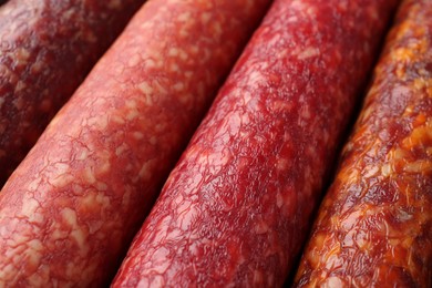 Photo of Different tasty smoked sausages as background, closeup