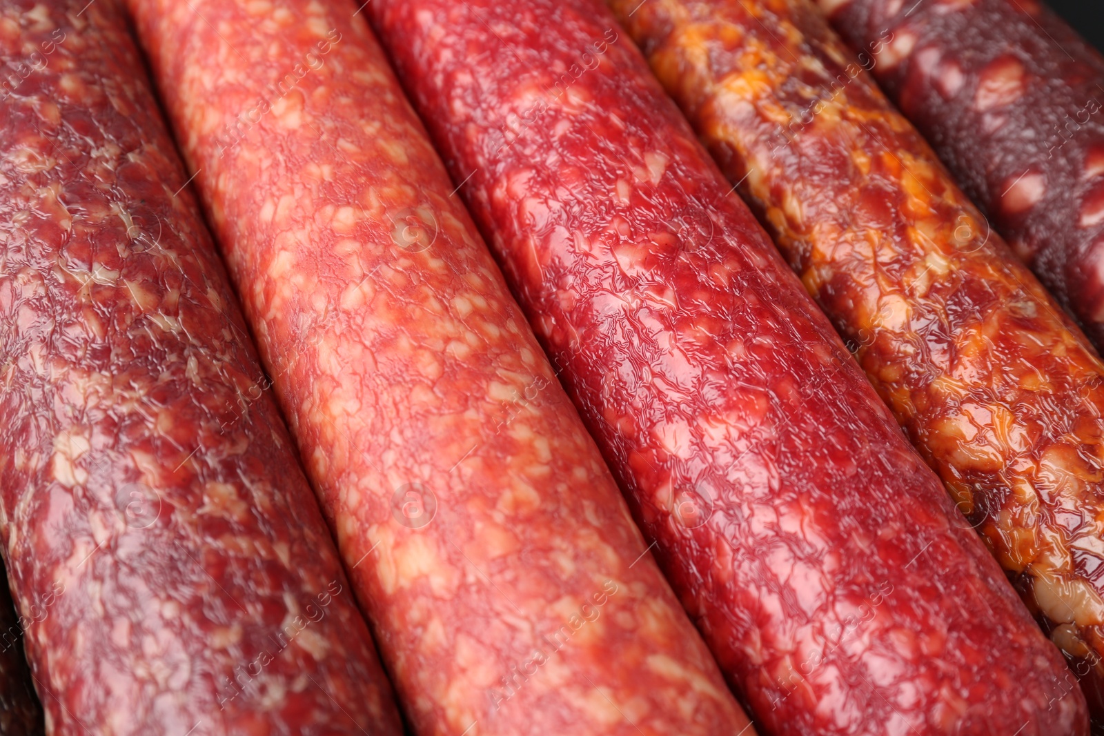 Photo of Different tasty smoked sausages as background, closeup