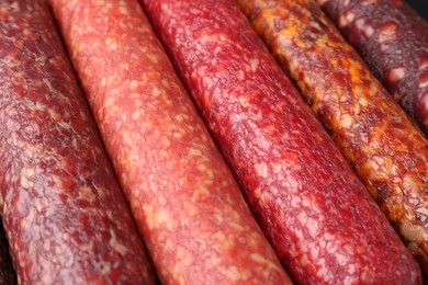 Photo of Different tasty smoked sausages as background, closeup