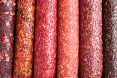 Photo of Different tasty smoked sausages as background, top view