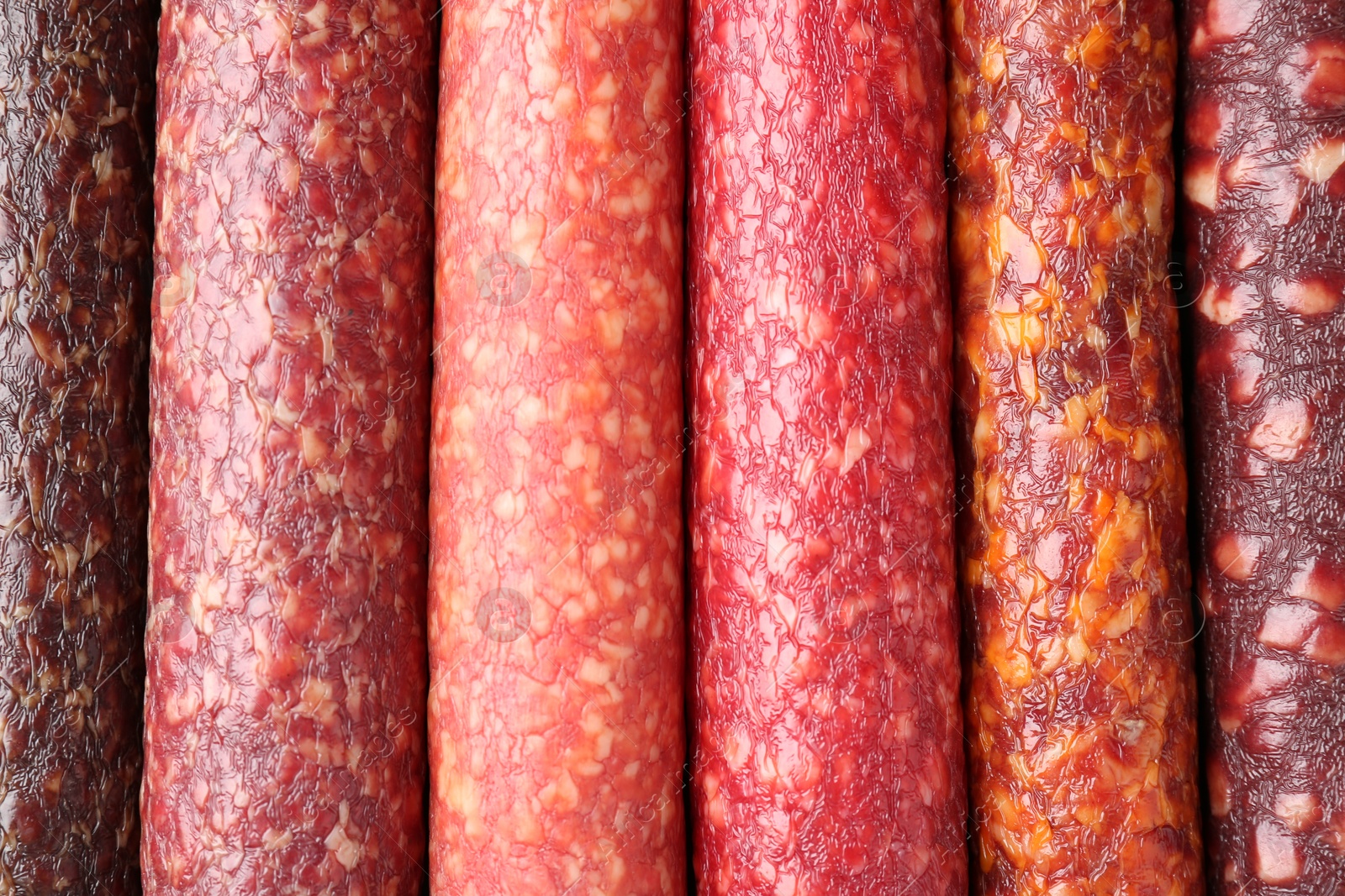 Photo of Different tasty smoked sausages as background, top view