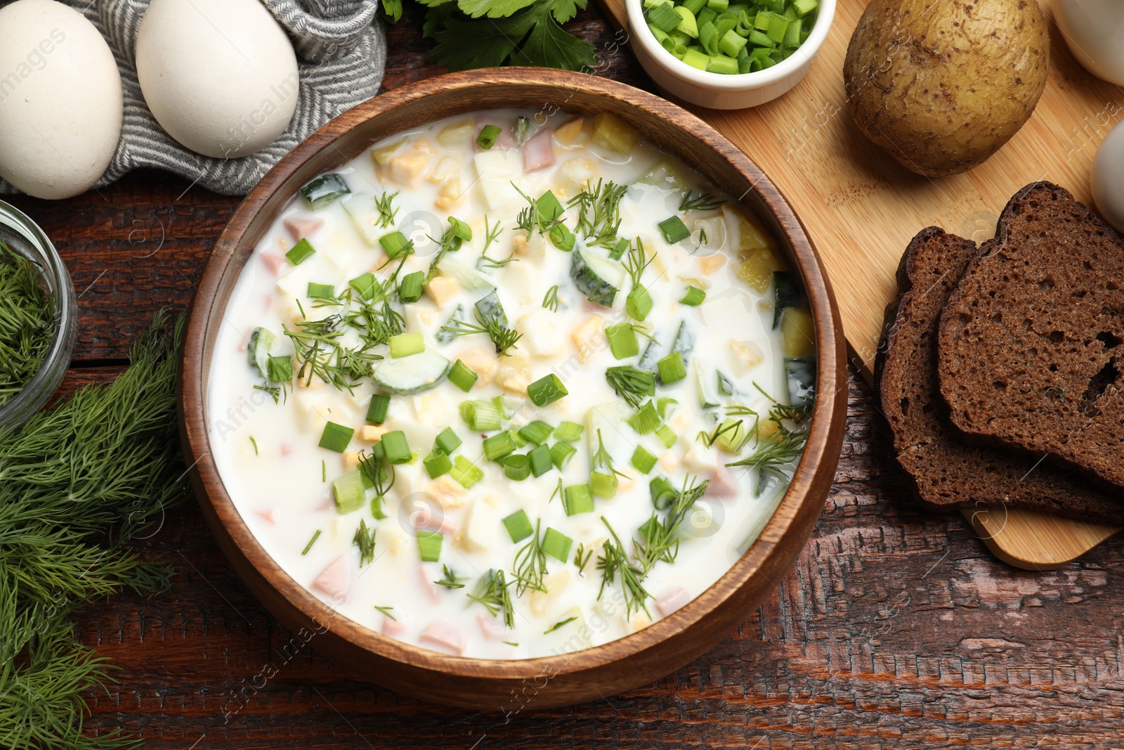 Photo of Delicious okroshka soup with kefir and bread on wooden table, flat lay