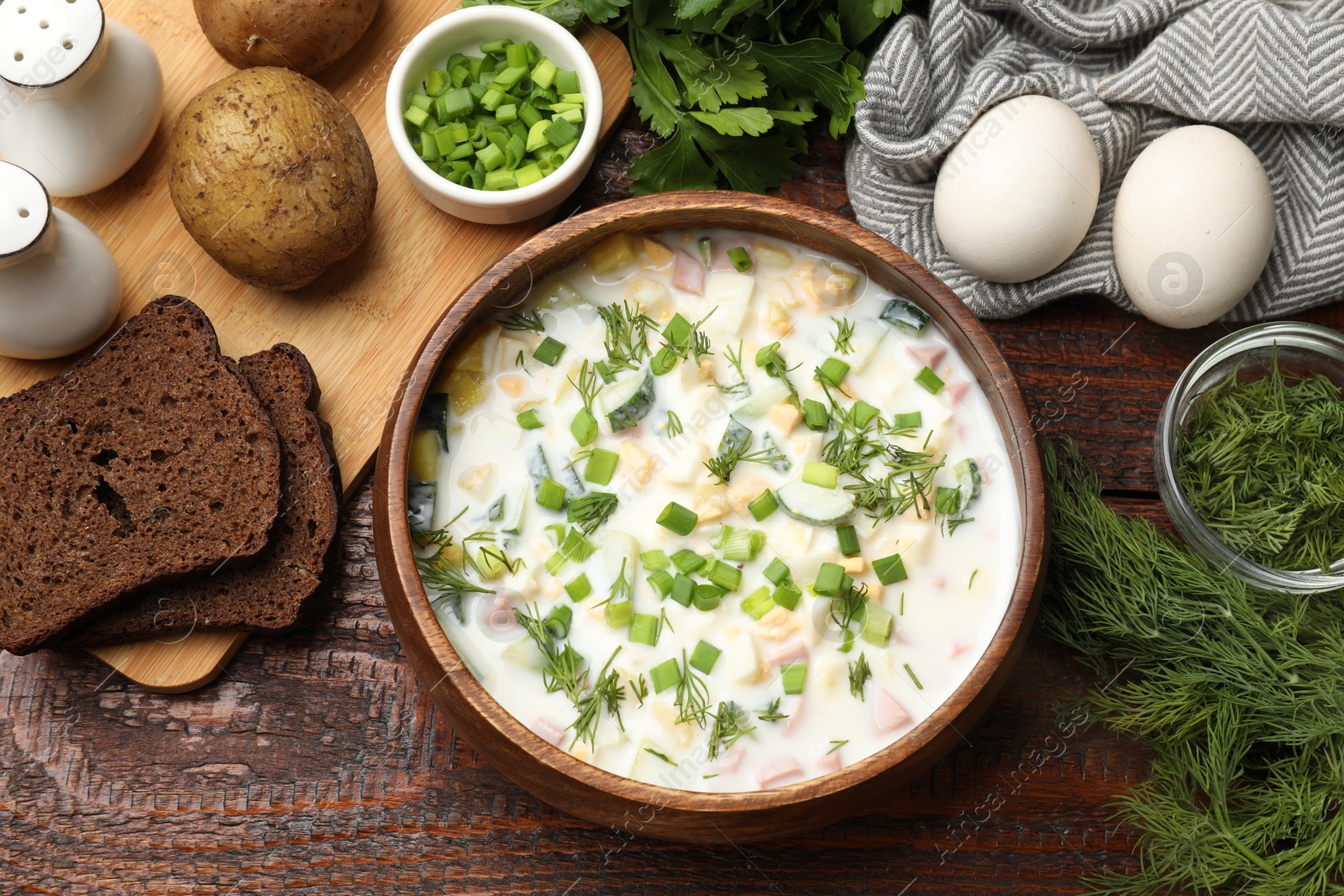 Photo of Delicious okroshka soup with kefir and bread on wooden table, flat lay