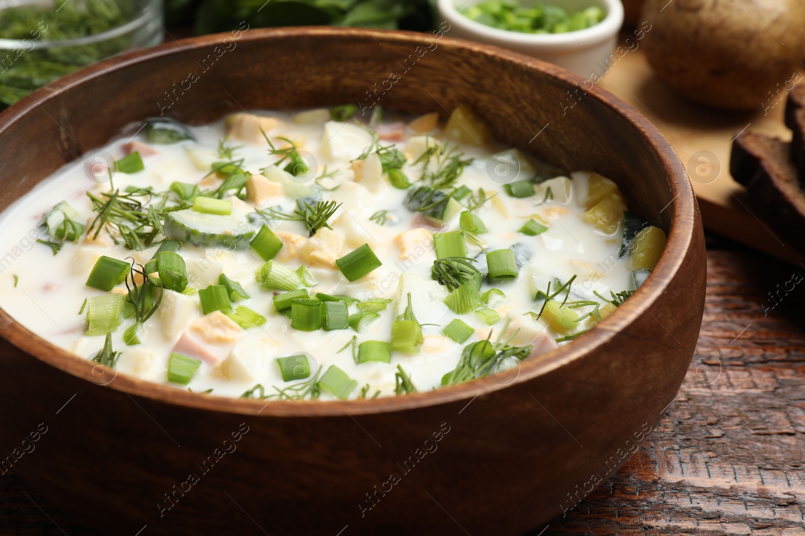 Photo of Delicious okroshka soup with kefir on wooden table, closeup