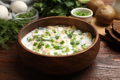 Photo of Delicious okroshka soup with kefir on wooden table, closeup