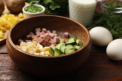 Photo of Different ingredients for okroshka soup on wooden table, closeup