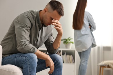 Photo of Offended couple ignoring each other at home, selective focus