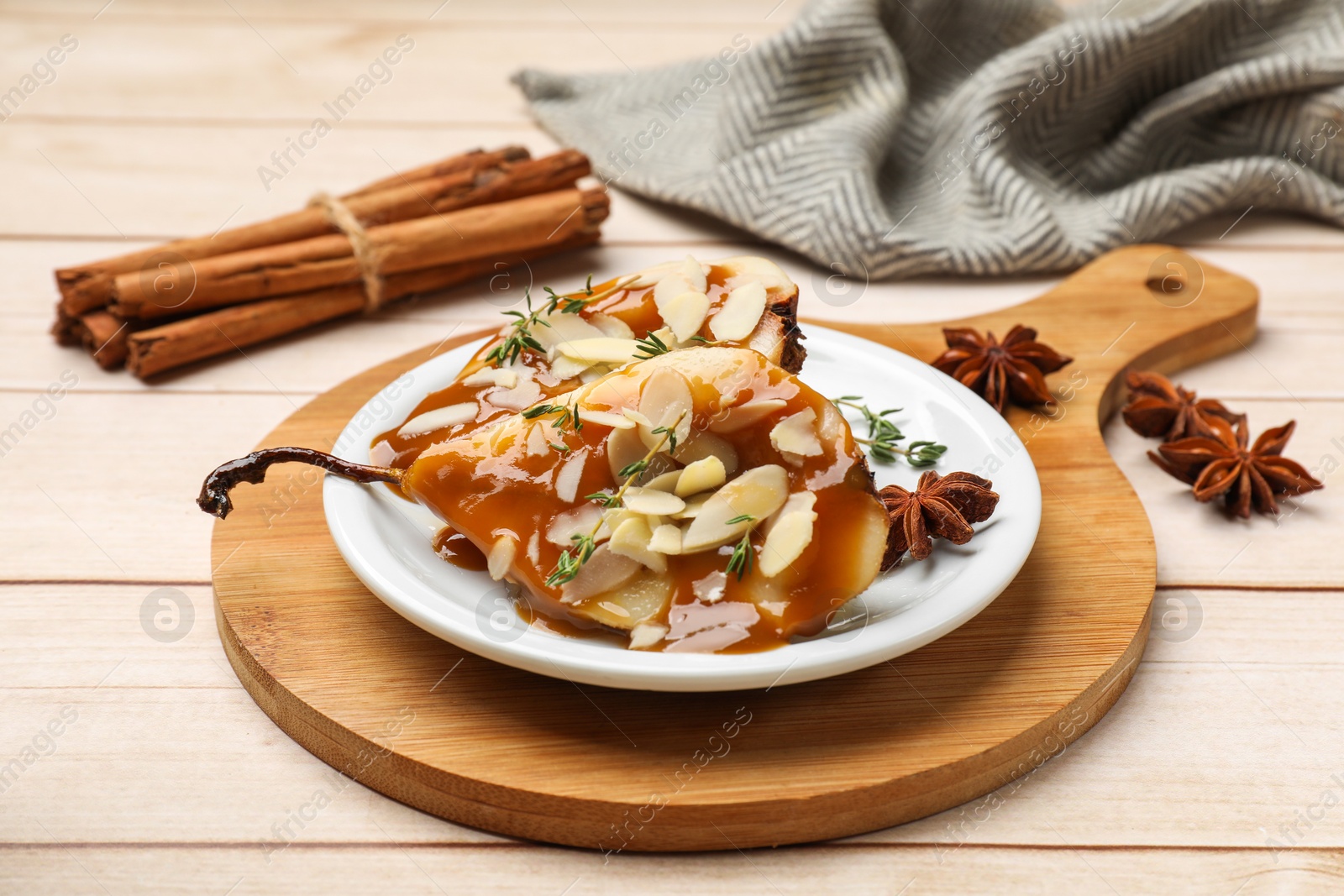 Photo of Delicious pears with caramel sauce, almond flakes and spices on white wooden table