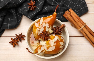 Photo of Delicious pears with caramel sauce, almond flakes and spices on white wooden table, flat lay