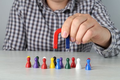 Photo of Man with magnet attracting colorful game pieces at light table, closeup