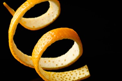 One fresh orange peel on black background, closeup. Space for text