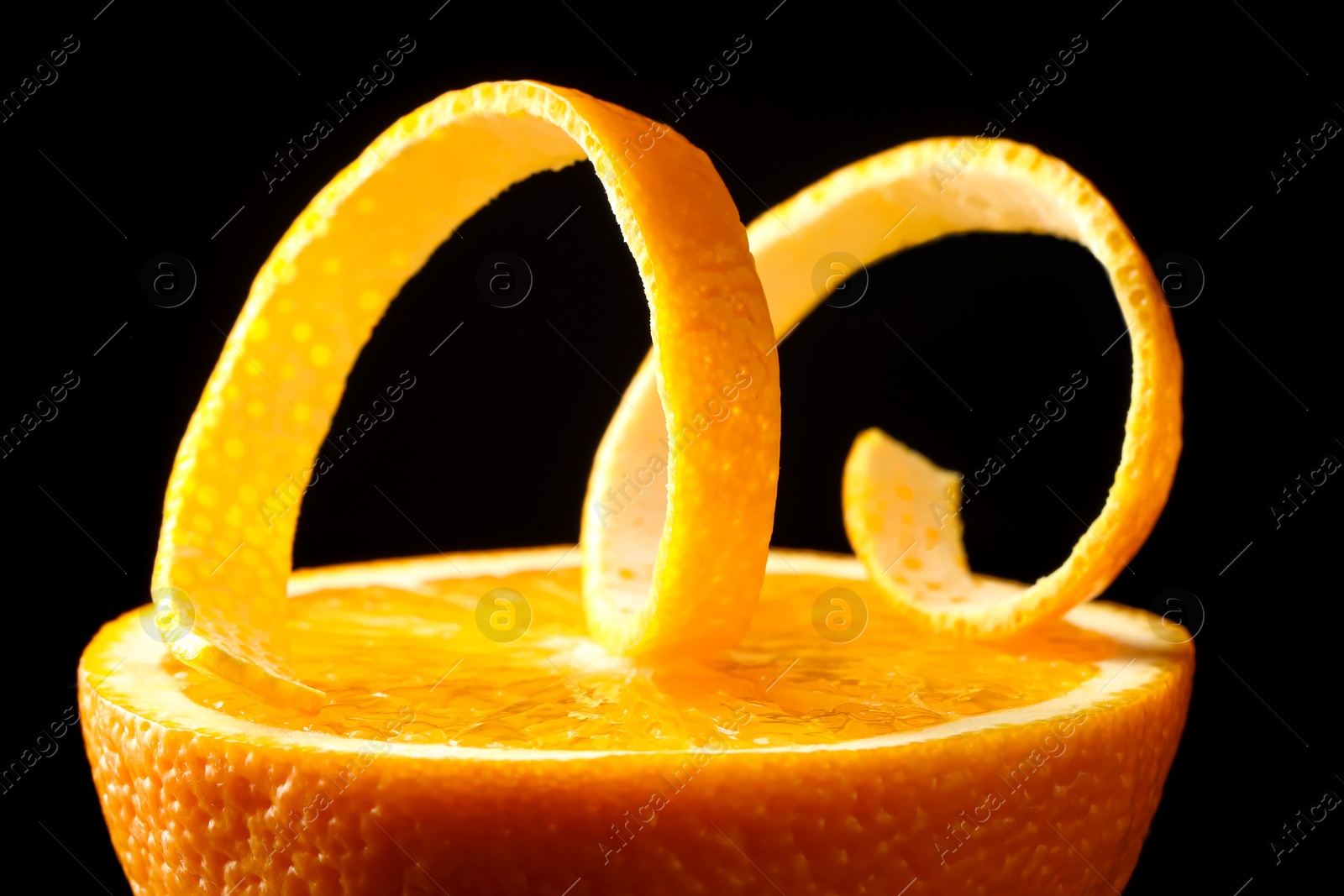 Photo of Fresh orange peel and half of fruit on black background, closeup