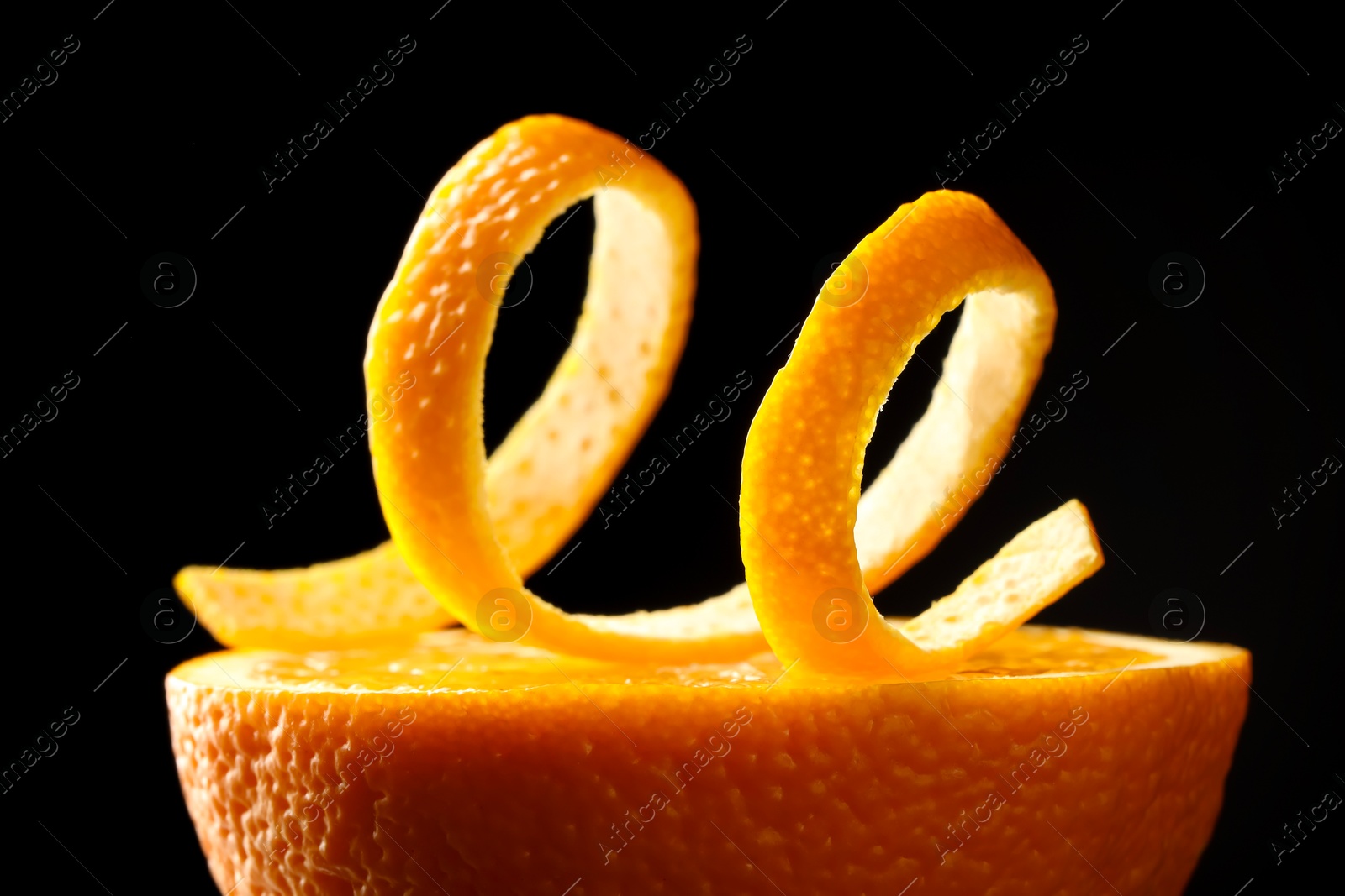 Photo of Fresh orange peel and half of fruit on black background, closeup