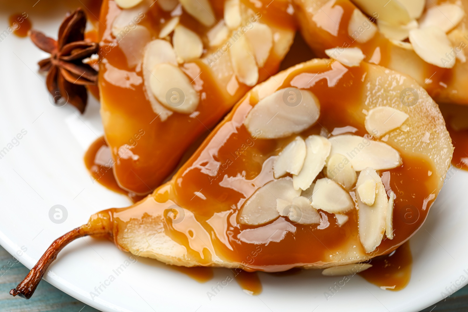 Photo of Delicious pears with caramel sauce and almond flakes on plate, closeup