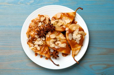 Photo of Delicious pears with caramel sauce, almond flakes and anise stars on light blue wooden table, top view