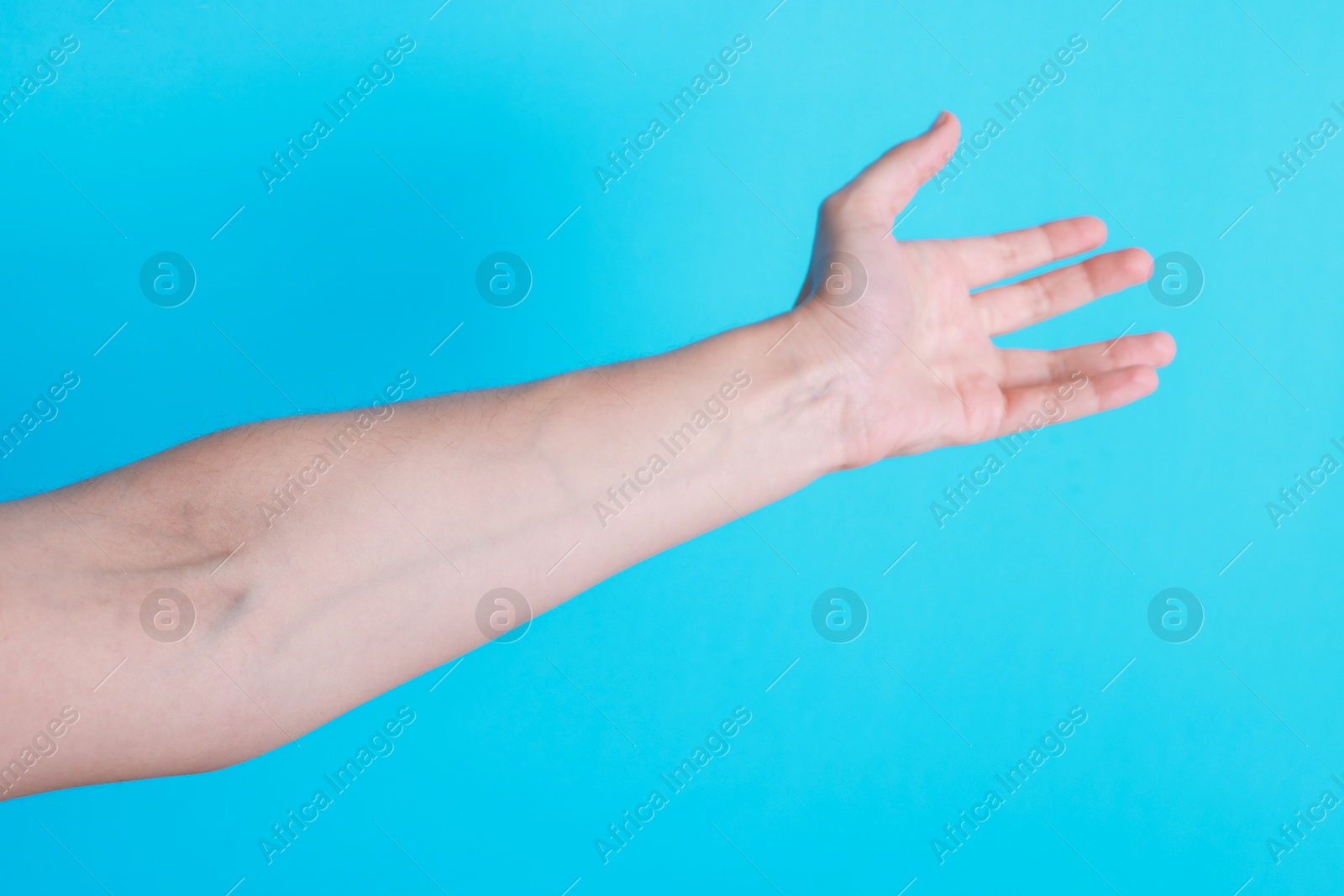 Photo of Woman with visible hand veins on light blue background, closeup