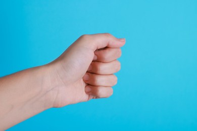 Photo of Woman with visible hand veins on light blue background, closeup