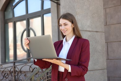 Photo of Portrait of young woman with laptop wearing stylish suit outdoors