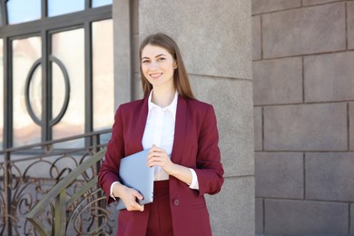 Photo of Portrait of young woman with laptop wearing stylish suit outdoors