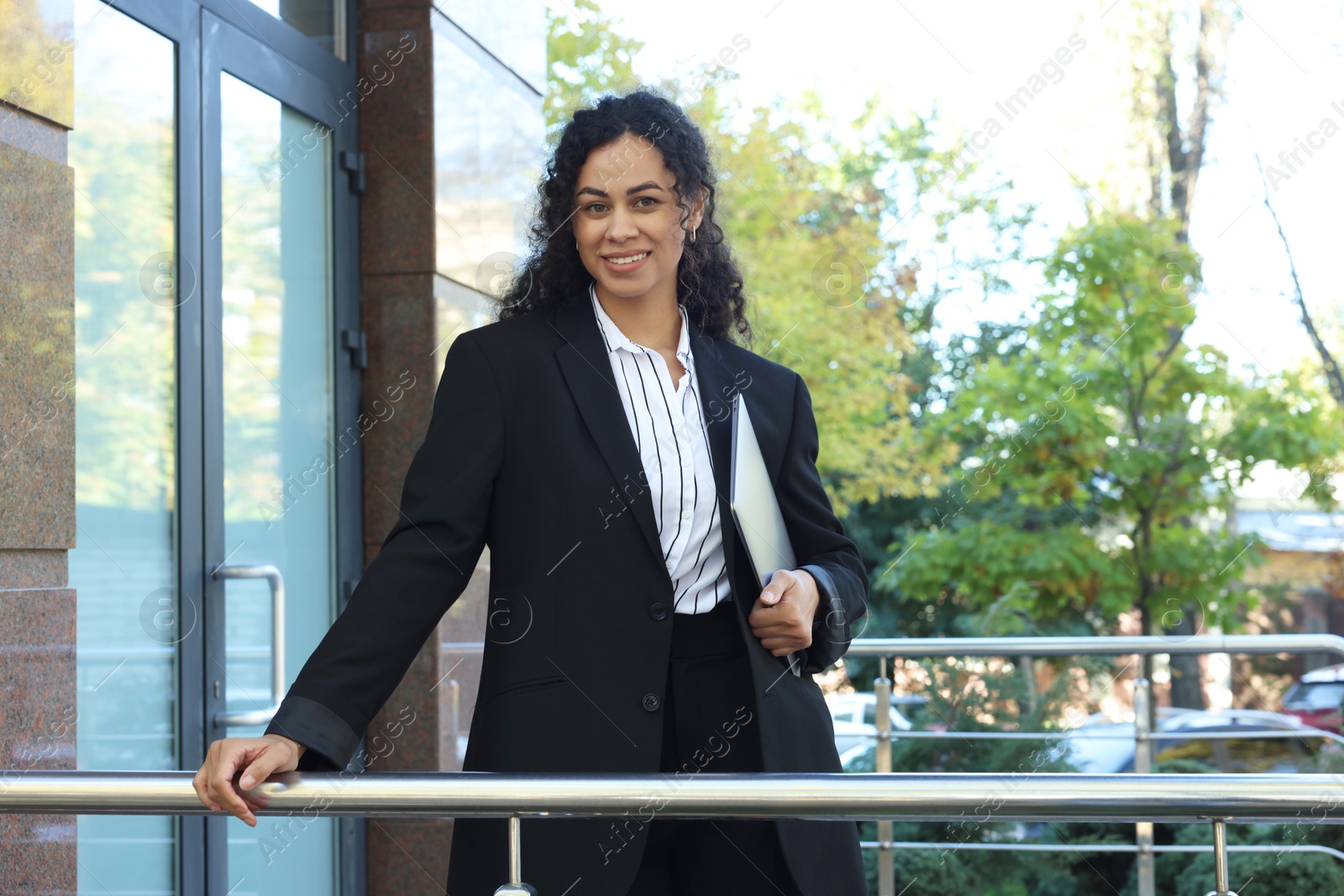 Photo of Portrait of young woman with laptop wearing stylish suit outdoors