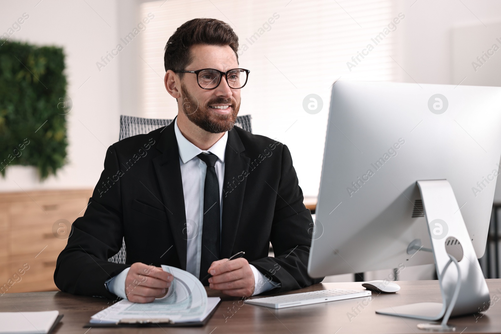 Photo of Man working with document at table in office