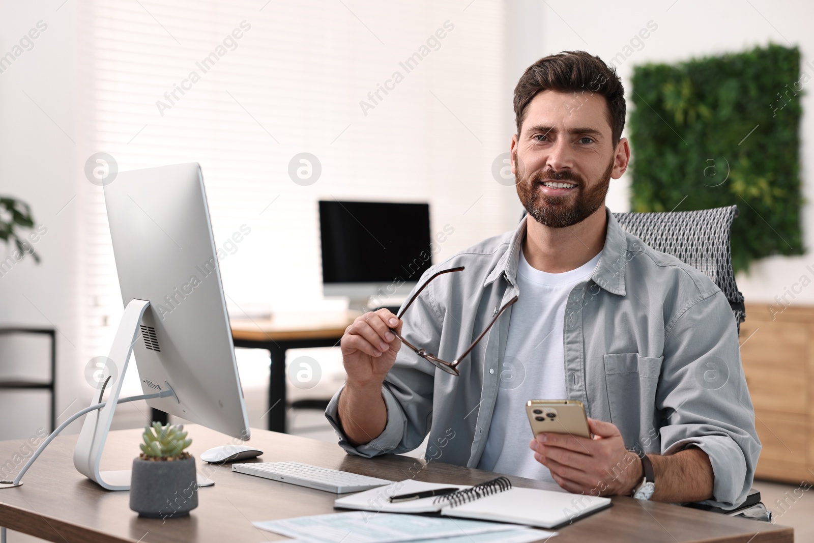 Photo of Man with smartphone working at table in office