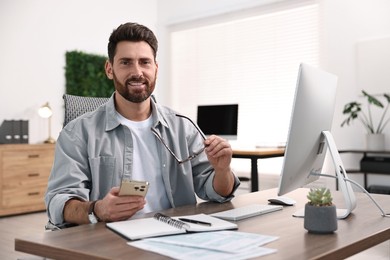 Photo of Man with smartphone working at table in office