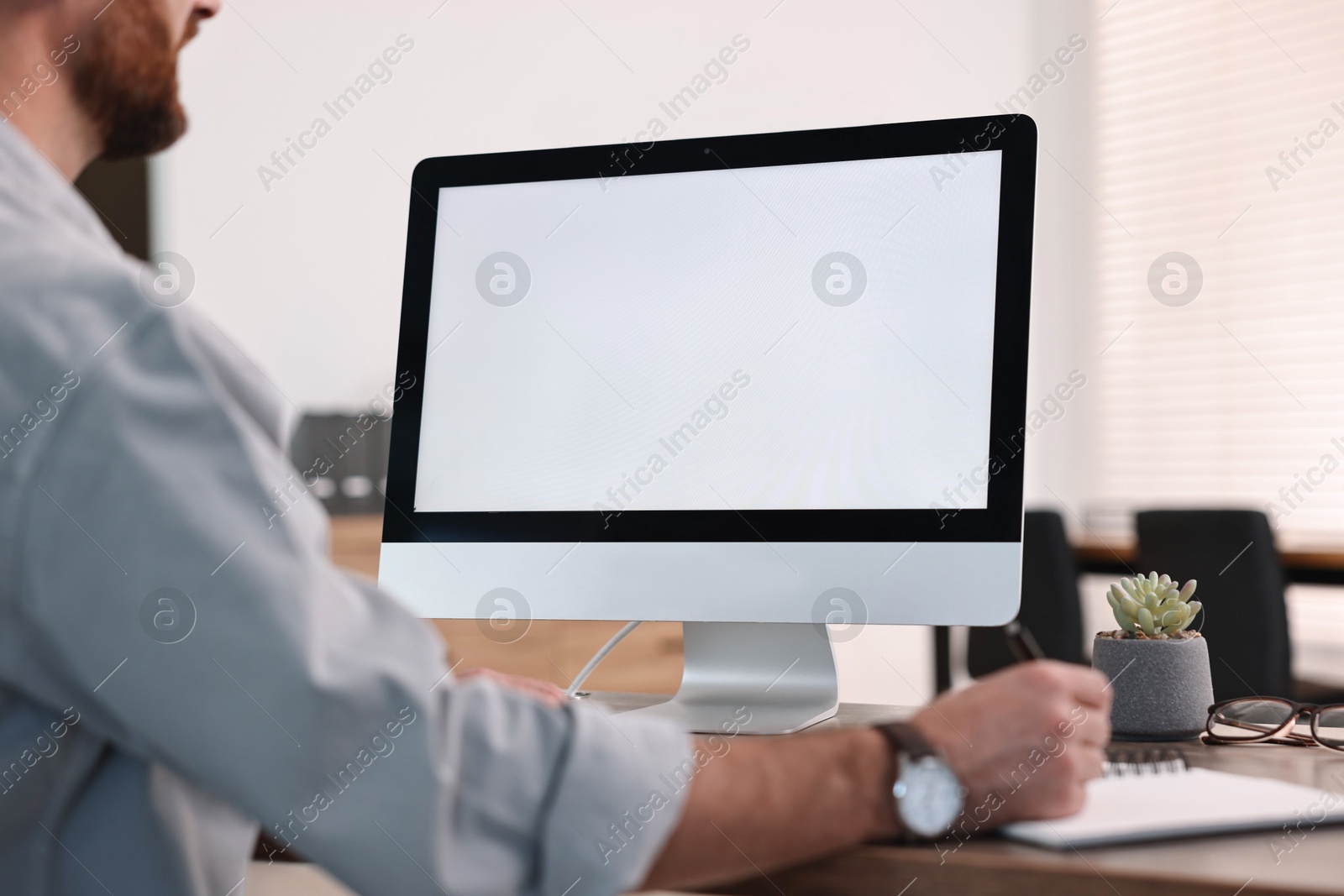 Photo of Man working on computer at table in office, closeup