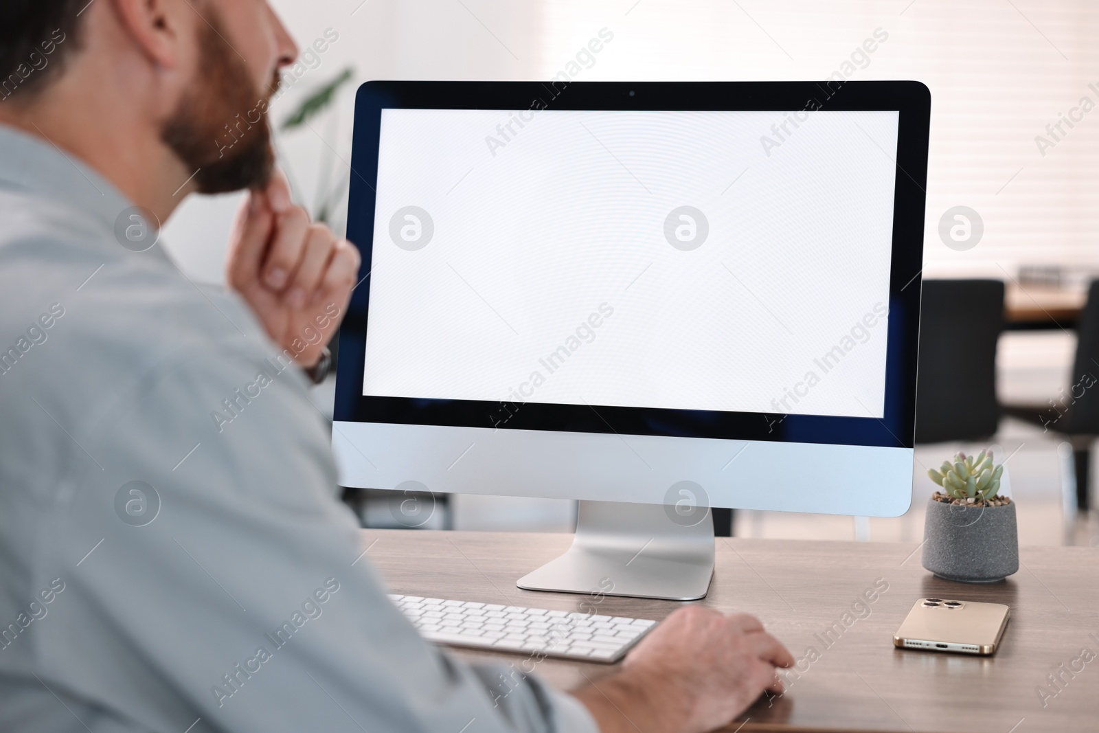 Photo of Man working on computer at table in office, closeup