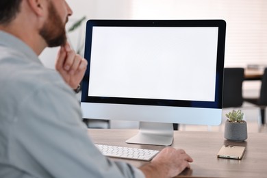 Photo of Man working on computer at table in office, closeup