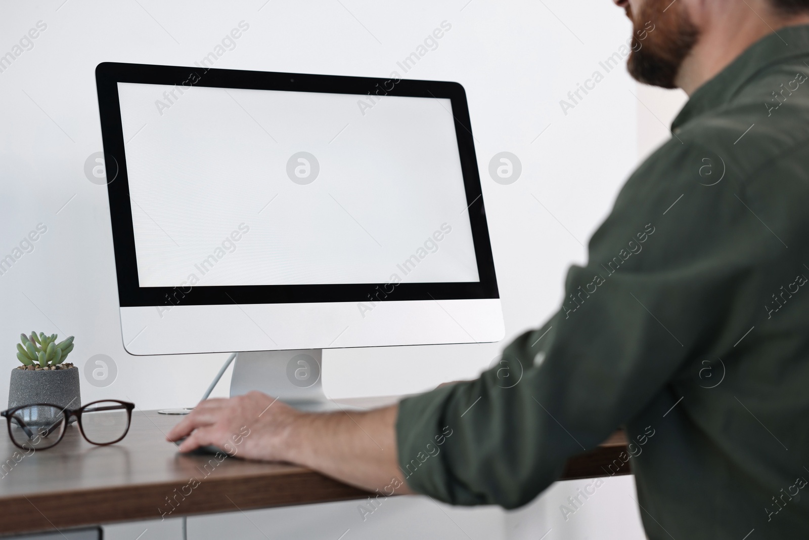 Photo of Man working on computer at table in office, closeup