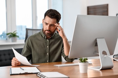 Photo of Man with document working at table in office