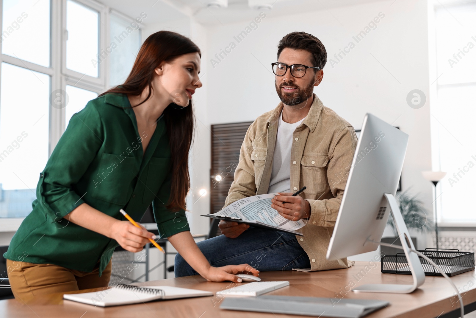 Photo of Colleagues working with computer at desk in office