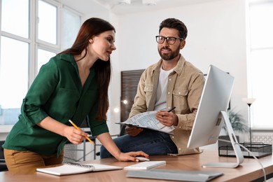 Photo of Colleagues working with computer at desk in office