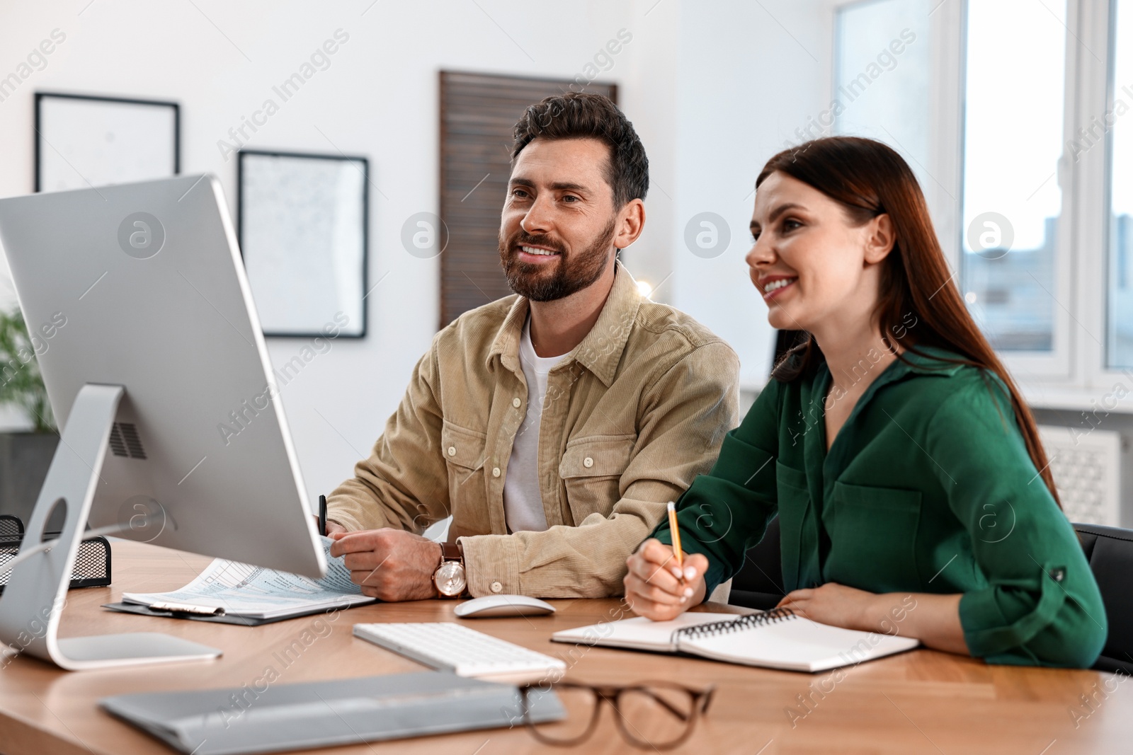 Photo of Colleagues working with computer at desk in office