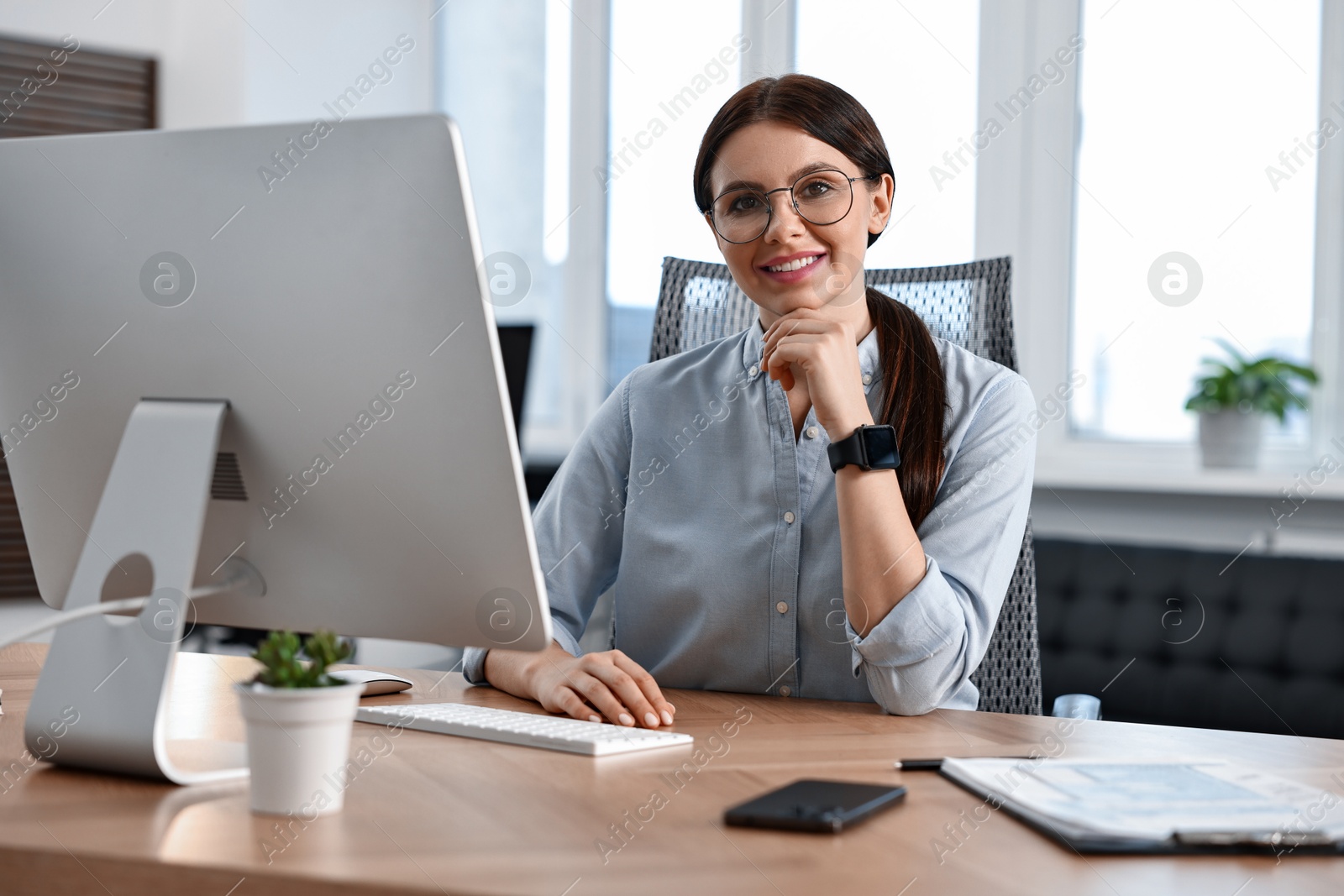 Photo of Portrait of woman at table with computer in office