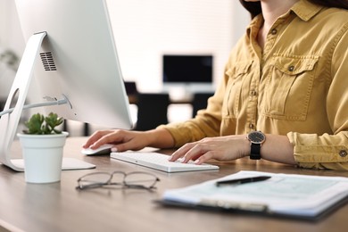 Photo of Woman working on computer at table in office, closeup