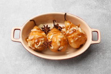 Photo of Delicious pears with caramel sauce, almond flakes and anise stars on grey table, top view