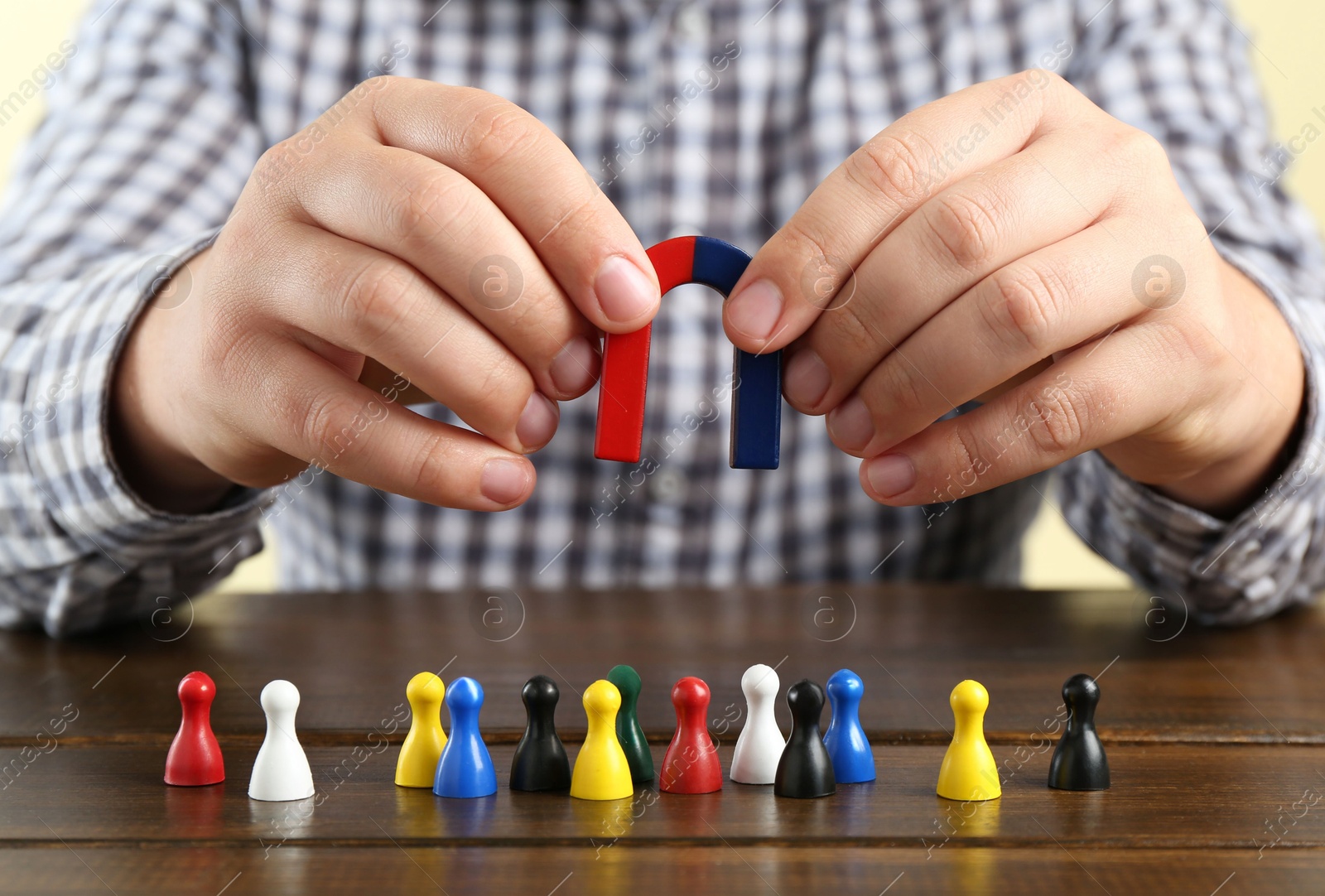 Photo of Man with magnet attracting game pieces at wooden table, closeup