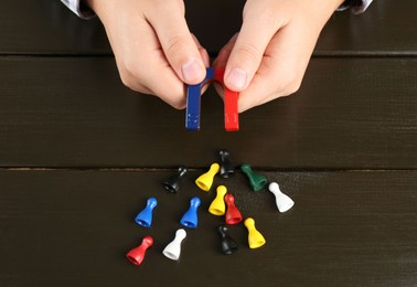 Photo of Man with magnet attracting game pieces at wooden table, above view