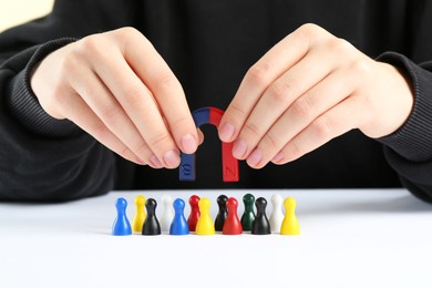 Photo of Woman with magnet attracting game pieces at white table, closeup