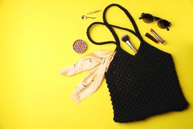 Photo of Flat lay composition with macrame shopping bag and makeup products on yellow background. Space for text