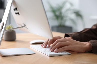 Photo of Man working on computer at wooden desk in office, closeup